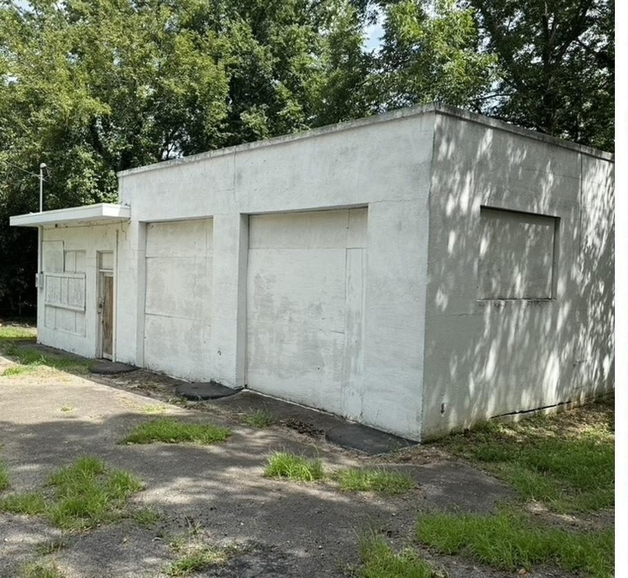 The existing white concrete-block building at 1300 Glenn Street, shaded by trees.